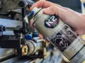 Ręka aplikuje biały smar litowy z PTFE na ruchome części mechanizmu. Idealne biały smar zastosowanie do smarowania i ochrony.