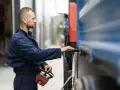 Mężczyzna w niebieskim kombinezonie obsługuje zdalnie sterowanie i laptopa podczas odbioru UDT.