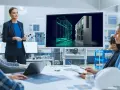 Zespół omawia projekt z wykorzystaniem oprogramowania Siemens PLM. Na ekranie widoczny jest trójwymiarowy model szafy sterowniczej.