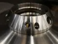 Metalowy element z otworami, przypominający kołnierz. To przykład precyzyjnej obróbki, która może być częścią procesu napawania.