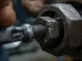 Ręka próbuje odkręcić obrobioną śrubę sześciokątną za pomocą klucza.