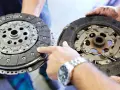 Dwie tarcze sprzęgła, jedna nowa, druga zużyta, prezentowane przez mechanika. Widać mechanizm sprzęgła samonastawne.
