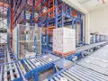 Automatyczne magazyny z zaawansowanymi systemami transportu bliskiego. Palety z produktami przemieszczają się po taśmociągach w hali.