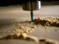 Frezarka CNC obrabia drewno, tworząc wióry. Optymalne parametry skrawania zapewniają precyzję i gładkość powierzchni.