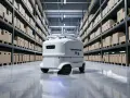 Nowoczesny robot AMR porusza się po magazynie pełnym paczek.