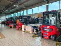 Wózki widłowe i palety z częściami na hali produkcyjnej. Drogi transportowe są gotowe do pracy.