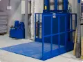 Niebieska winda magazynowa z hydraulicznym podnośnikiem ułatwia transport towarów.