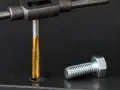 Gwintowanie aluminium: złoty gwintownik wkręcany w metal, obok leży śruba.