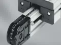 Mechanizm z łańcuchem i rolkami, część precyzyjnych przekładni łańcuchowych, porusza się po aluminiowej szynie.