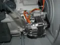 Silnik pralki z paskiem napędowym i przewodami. Widać elementy mechaniczne, które wpływają na wzór na prędkość obrotową bębna.