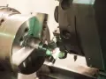 Precyzyjne toczenie aluminium na obrabiarce CNC. Metalowy element obraca się, a narzędzie nadaje mu kształt.