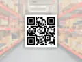 Kod kreskowy QR na tle magazynu z półkami pełnymi paczek. Szybkie skanowanie ułatwia zarządzanie zapasami.