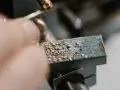 Precyzyjne gwintowanie prętów na maszynie. Wióry metalu pokrywają obrabiany element.