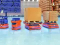 Pomarańczowe roboty AMR, czyli zautomatyzowane wozy magazynowe, przewożą paczki i pojemniki w nowoczesnym magazynie.