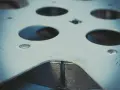 Metalowa płyta z wieloma okrągłymi otworami, widoczne ślady po rozwiercaniu.