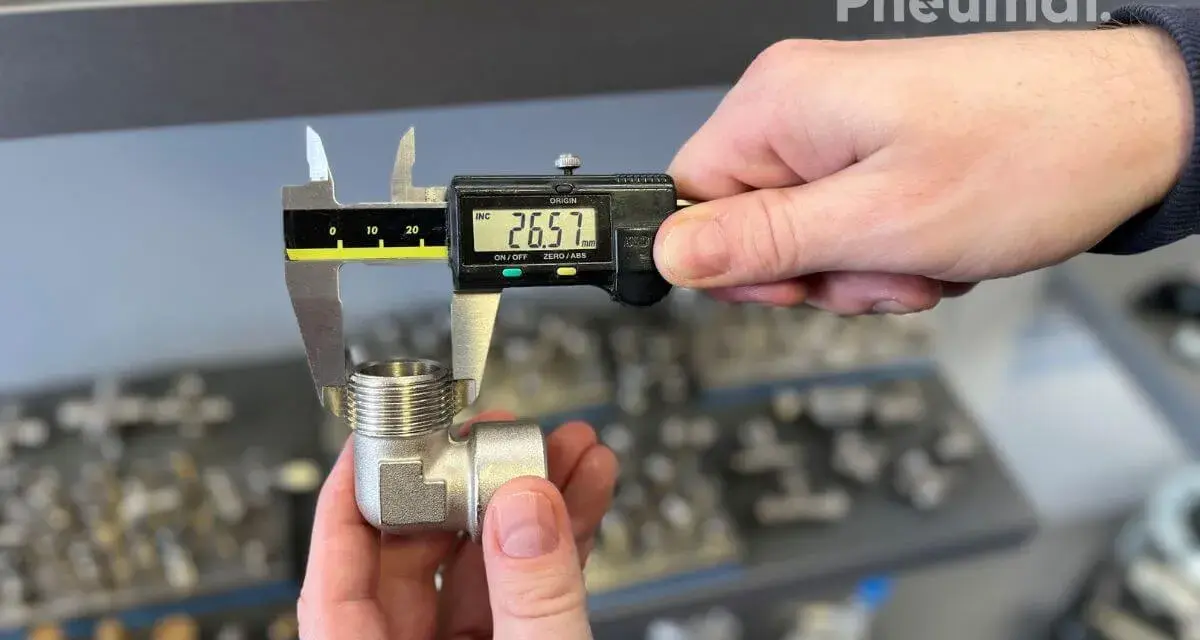 Precyzyjne pomiary gwintów zewnętrznych kolanka pneumatycznego suwmiarką cyfrową. Wynik 26.57 mm.