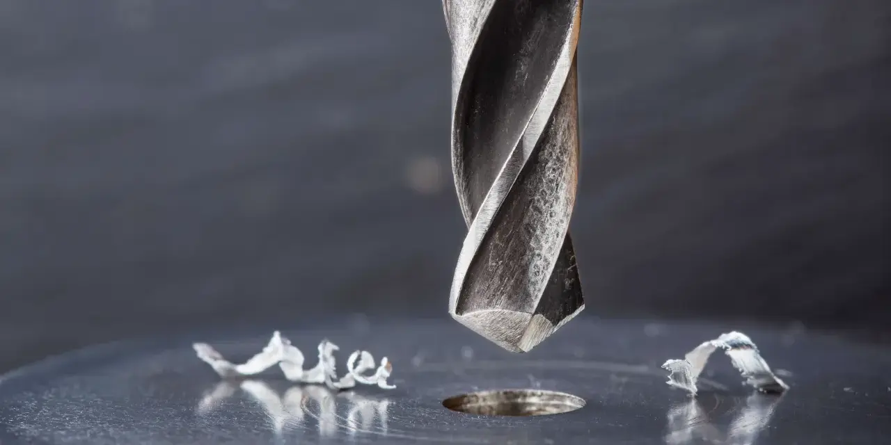 Metalowe wióry wokół świeżo wywierconego otworu świadczą o sile i precyzji najtwardszych wierteł do metalu.