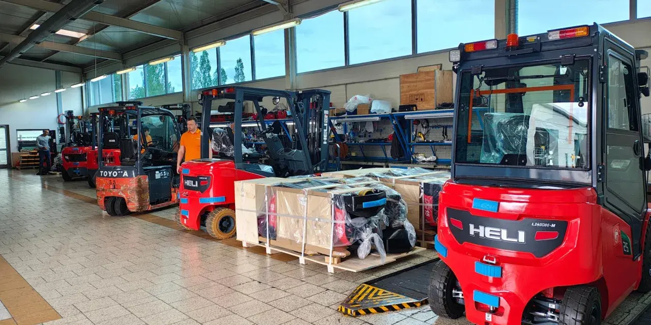 Wózki widłowe i palety z częściami na hali produkcyjnej. Drogi transportowe są gotowe do pracy.