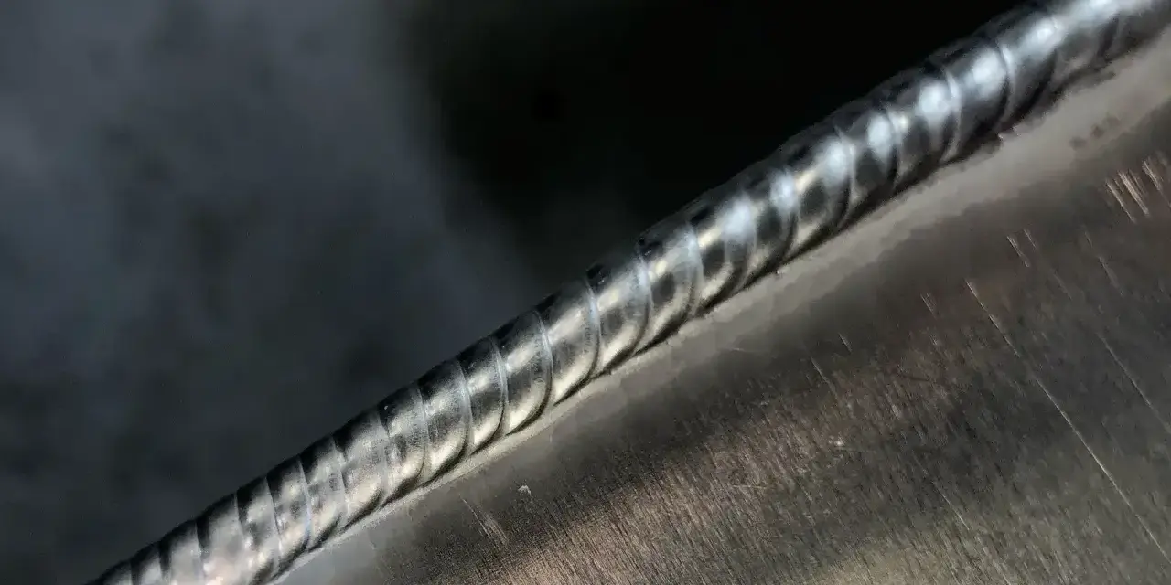 Precyzyjne spawanie aluminium, widoczny ścieg spawalniczy o regularnych falach.