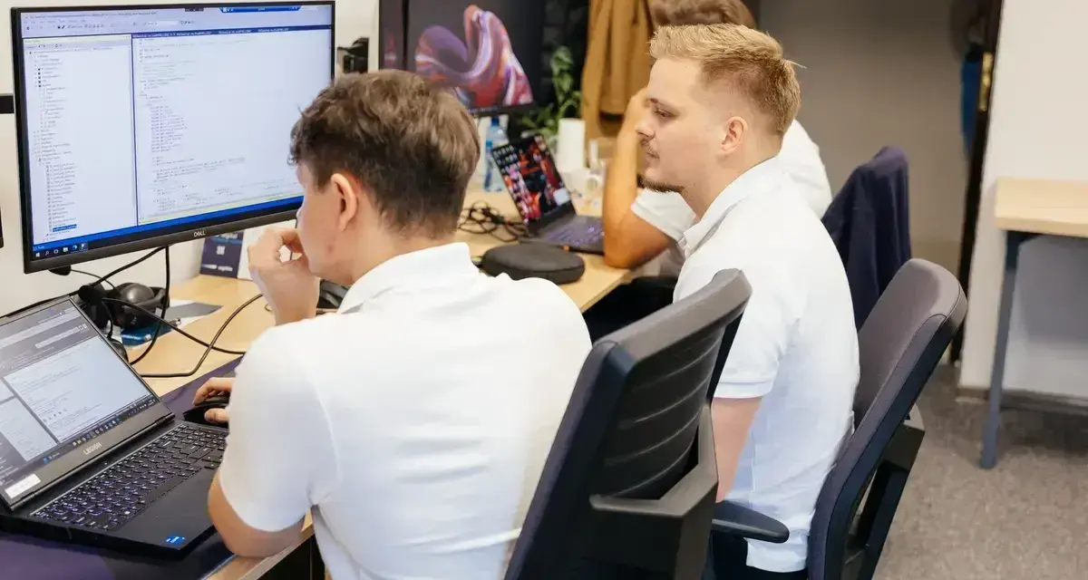 Programiści pracują nad kodem, analizując dane i rozwiązując queris cmms.