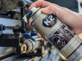 Ręka aplikuje biały smar litowy z PTFE na ruchome części mechanizmu. Idealne biały smar zastosowanie do smarowania i ochrony.