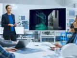 Zespół omawia projekt z wykorzystaniem oprogramowania Siemens PLM. Na ekranie widoczny jest trójwymiarowy model szafy sterowniczej.