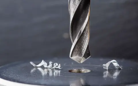 Metalowe wióry wokół świeżo wywierconego otworu świadczą o sile i precyzji najtwardszych wierteł do metalu.