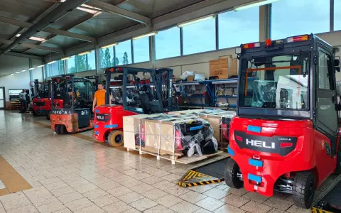 Wózki widłowe i palety z częściami na hali produkcyjnej. Drogi transportowe są gotowe do pracy.