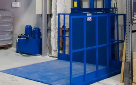 Niebieska winda magazynowa z hydraulicznym podnośnikiem ułatwia transport towarów.