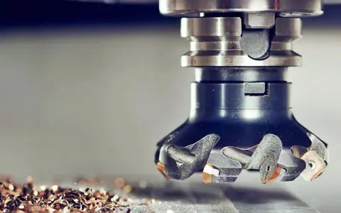 Głowica frezarska w akcji, precyzyjna obróbka CNC tworzy metalowe wióry.