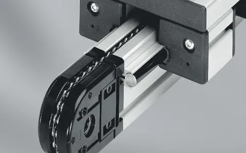 Mechanizm z łańcuchem i rolkami, część precyzyjnych przekładni łańcuchowych, porusza się po aluminiowej szynie.