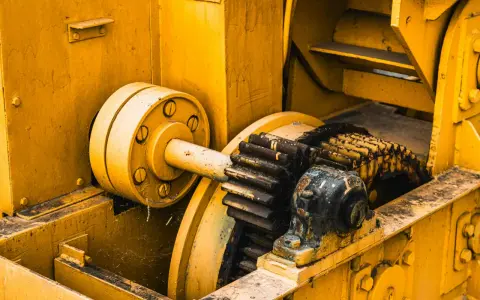 Żółta maszyna z zębatkami, gdzie różne rodzaje smarów chronią mechanizm przed zużyciem.