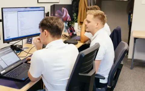 Programiści pracują nad kodem, analizując dane i rozwiązując queris cmms.
