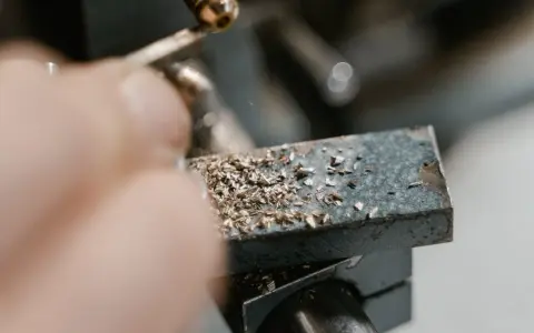 Precyzyjne gwintowanie prętów na maszynie. Wióry metalu pokrywają obrabiany element.