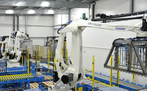 Nowoczesny magazyn automatyczny z robotami przemysłowymi. Taśmociągi i palety z produktami.