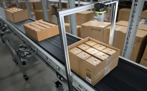 System pick by vision skanuje paczki na taśmie w magazynie.