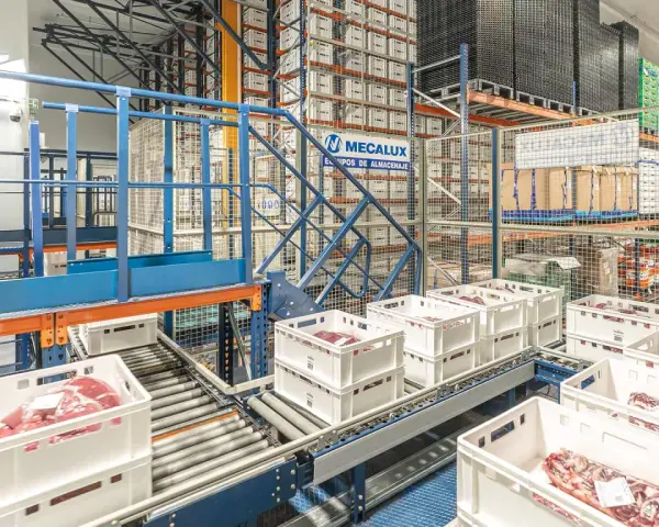 Automatyczny magazyn mięsa, gdzie białe skrzynki z produktami przemieszczają się po taśmociągu, zgodnie z zasadą FEFO.