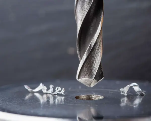 Metalowe wióry wokół świeżo wywierconego otworu świadczą o sile i precyzji najtwardszych wierteł do metalu.