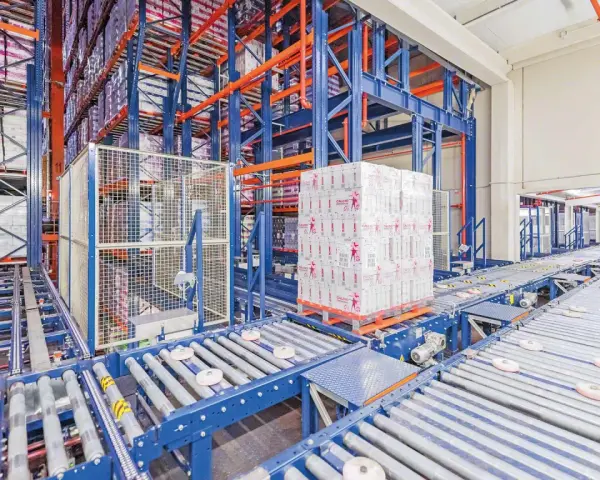 Automatyczne magazyny z zaawansowanymi systemami transportu bliskiego. Palety z produktami przemieszczają się po taśmociągach w hali.