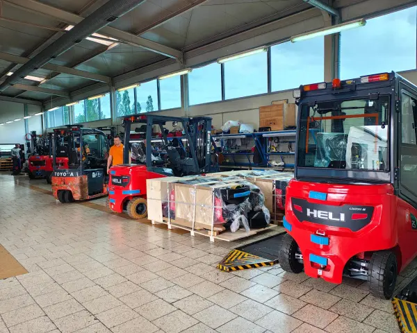 Wózki widłowe i palety z częściami na hali produkcyjnej. Drogi transportowe są gotowe do pracy.