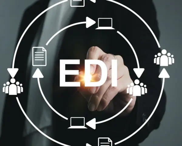 Ręka dotyka napisu EDI, otoczonego schematem przepływu danych między ludźmi i komputerami. System EDI usprawnia komunikację.