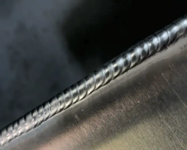 Precyzyjne spawanie aluminium, widoczny ścieg spawalniczy o regularnych falach.