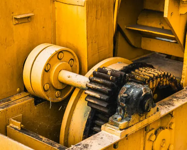 Żółta maszyna z zębatkami, gdzie różne rodzaje smarów chronią mechanizm przed zużyciem.