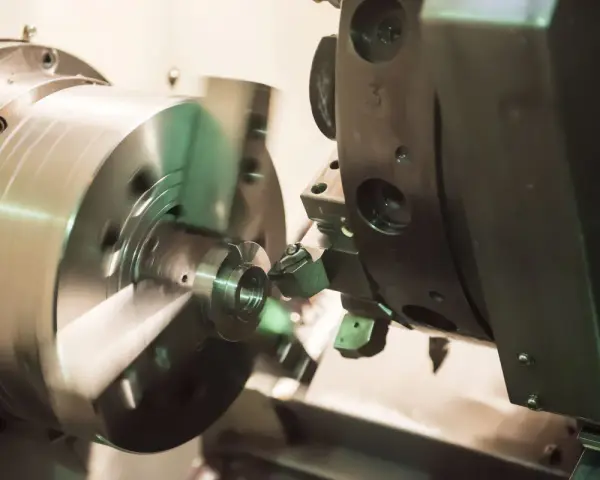 Precyzyjne toczenie aluminium na obrabiarce CNC. Metalowy element obraca się, a narzędzie nadaje mu kształt.