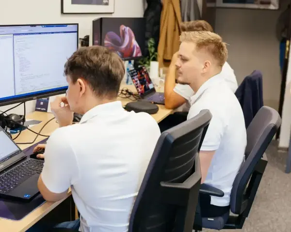 Programiści pracują nad kodem, analizując dane i rozwiązując queris cmms.