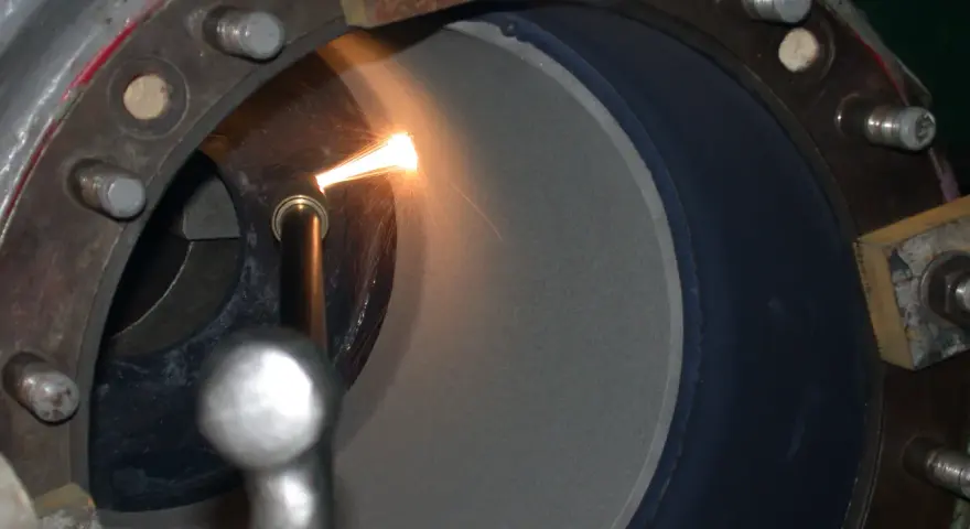 Proces metalizacji natryskowej w toku. Dysza aplikuje materiał na wewnętrzną powierzchnię cylindra, tworząc nową warstwę ochronną.