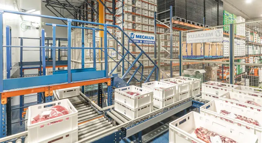 Automatyczny magazyn mięsa, gdzie białe skrzynki z produktami przemieszczają się po taśmociągu, zgodnie z zasadą FEFO.