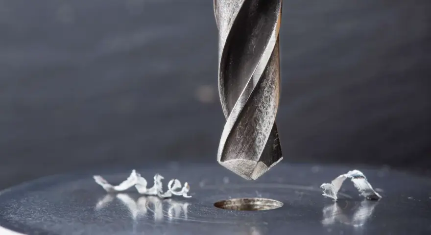 Metalowe wióry wokół świeżo wywierconego otworu świadczą o sile i precyzji najtwardszych wierteł do metalu.