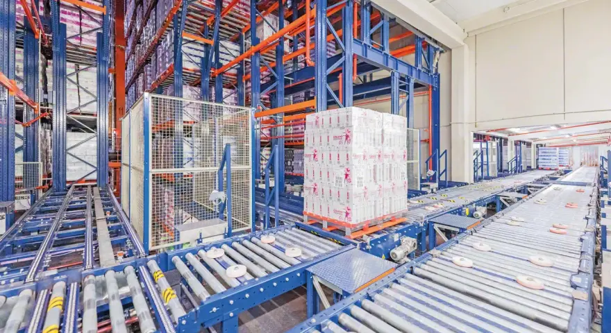 Automatyczne magazyny z zaawansowanymi systemami transportu bliskiego. Palety z produktami przemieszczają się po taśmociągach w hali.