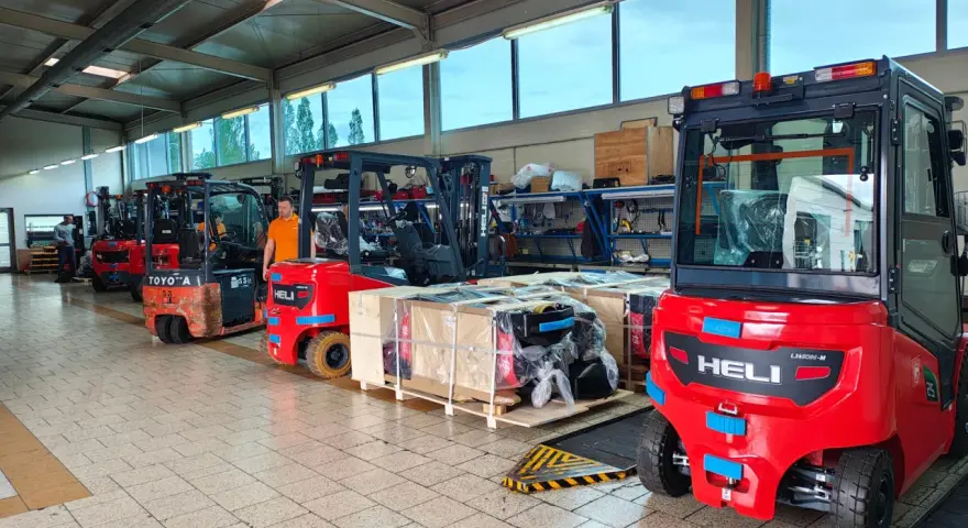 Wózki widłowe i palety z częściami na hali produkcyjnej. Drogi transportowe są gotowe do pracy.